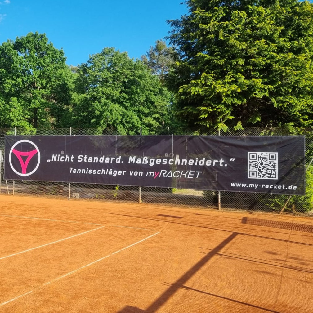 Schwarzer myRacket Windfänger mit Slogan am Zaun eines Sandplatzes – Nahansicht