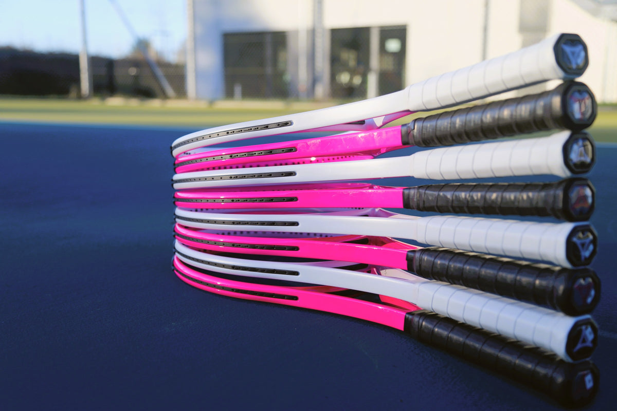 Gestapelte myRacket-Rahmen in Weiß und Pink auf blauem Hartplatz