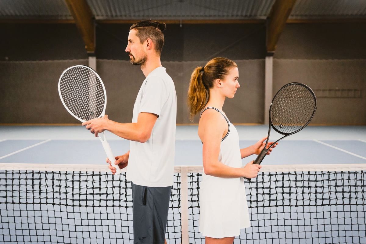 Jugador y jugadora espalda con espalda en la red, ambos con raquetas de tenis myRacket