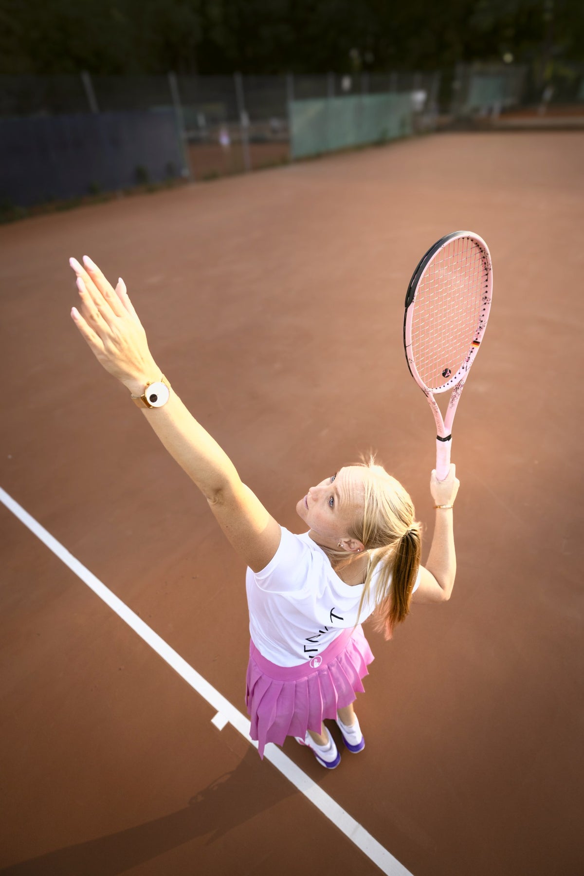 Joueuse avec une raquette sur mesure myRacket rose au service, photographiée d'en haut