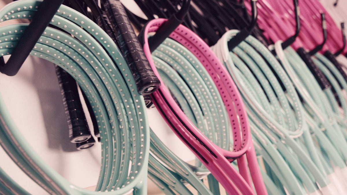 Muchos marcos myRacket sin encordar en menta, rosa y negro en el taller