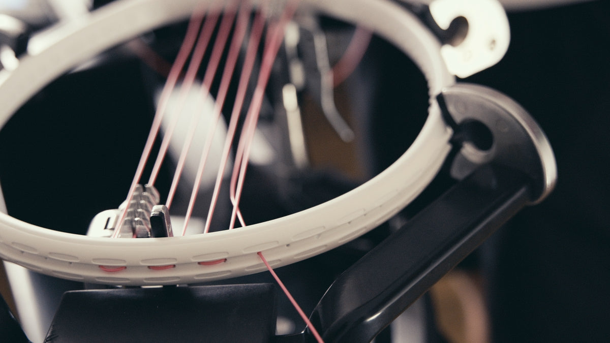 Weißer Rahmen in der Besaitungsmaschine, rosa Saite wird eingezogen