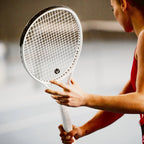 Hráčka kontroluje výpletový vzor a tlmič vibrácií svojej bielej rakety myRacket