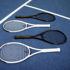 Čtyři rakety myRacket v černé a bílé na modrém tvrdém kurtu